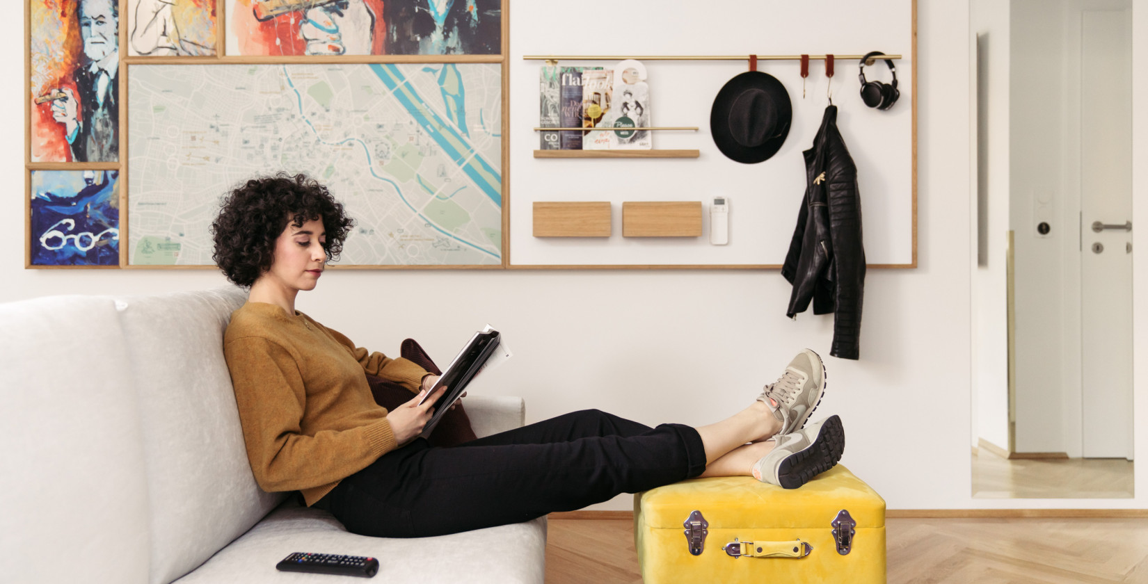 A woman sits on a sofa and looks at the tablet in a quietly furnished room