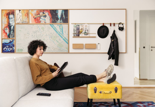 A woman sits on a sofa and looks at the tablet in a quietly furnished room