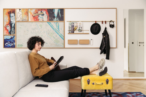 A woman sits on a sofa and looks at the tablet in a quietly furnished room
