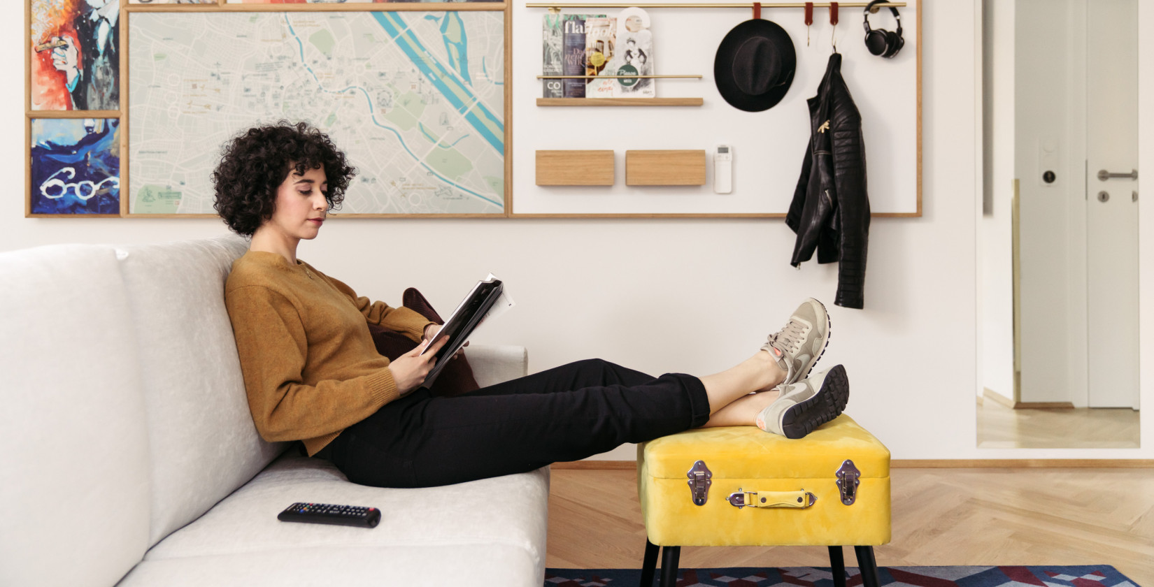 A woman sits on a sofa and looks at the tablet in a quietly furnished room