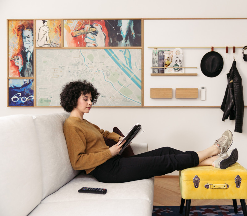 A woman sits on a sofa and looks at the tablet in a quietly furnished room