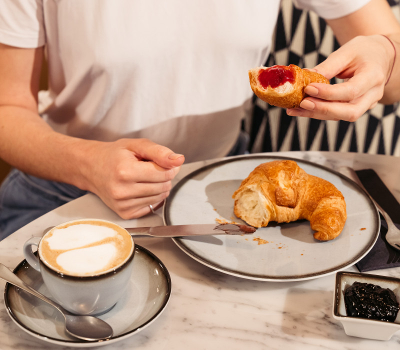 Frau hält ein Croissant mit Marmelade in der Hand