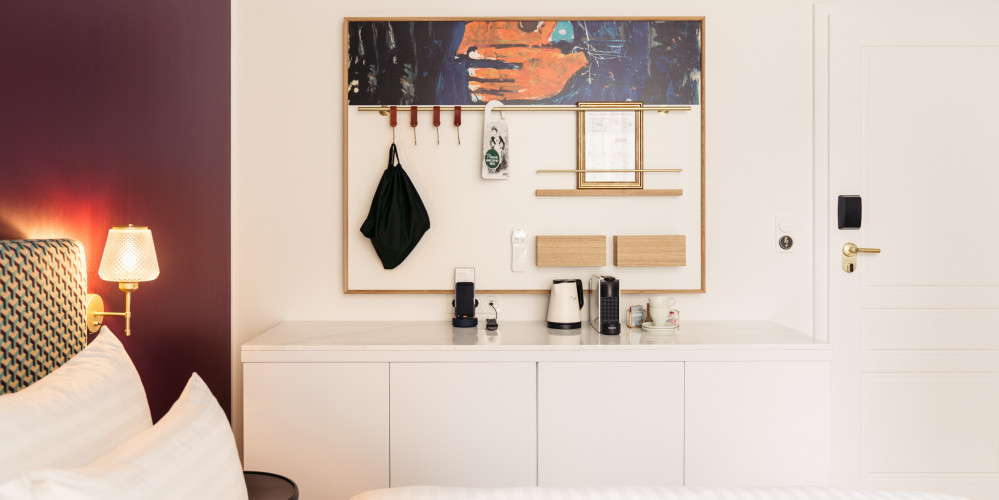 Cupboard with coffee and tea station under a memo board next to the bed