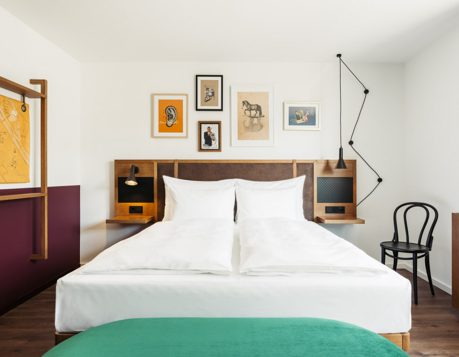 Green bench in front of a double bed in a family room 