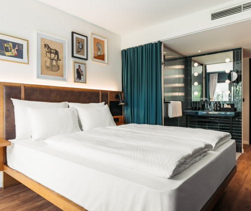 Doppelbett und offenes Badezimmer im Hotel Schani UNO City