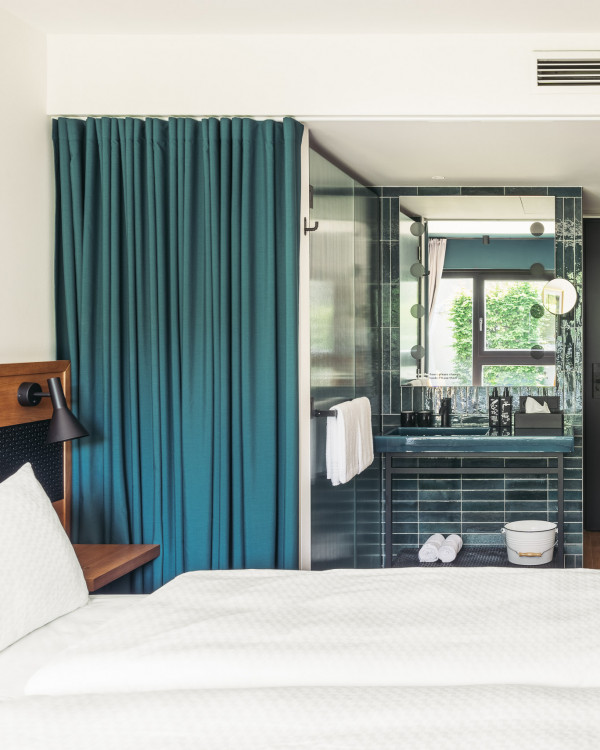 Doppelbett neben einem Badezimmer, das mit einem grünen Vorhang verschlossen werden kann