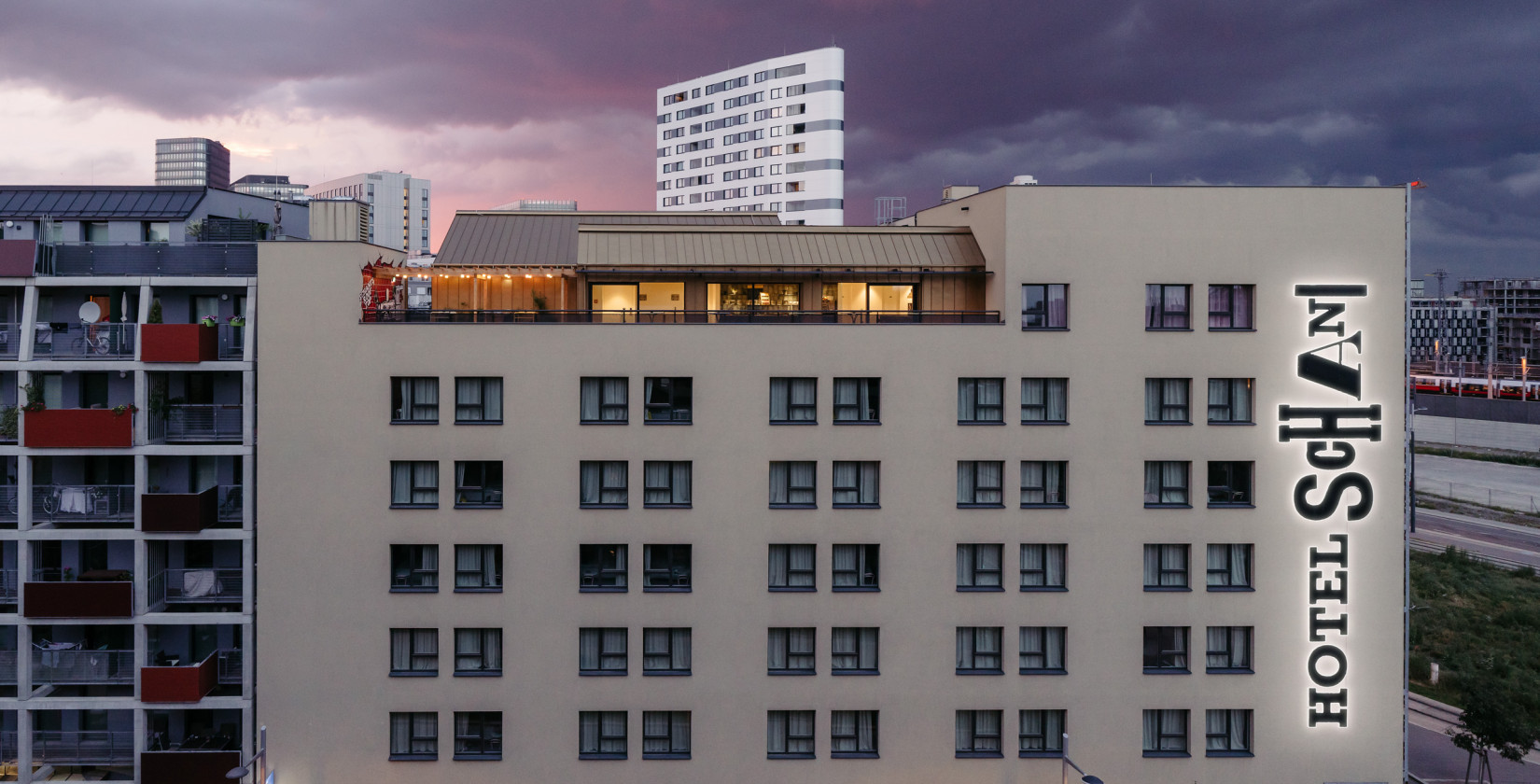 Hausfassade des Hotel Schani Wien mit Blick auf den Rooftop Event Space in der Dämmerung 