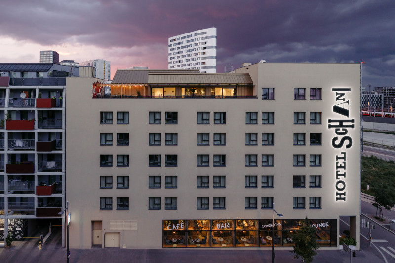 Hausfassade des Hotel Schani mit Blick auf den Rooftop Event Space in der Dämmerung 