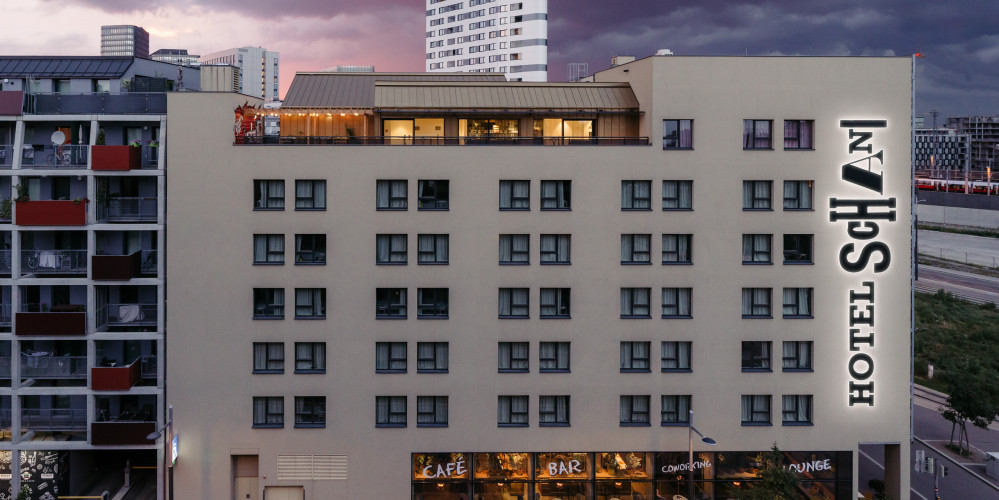 Hausfassade des Hotel Schani Wien mit Blick auf den Rooftop Event Space in der Dämmerung 