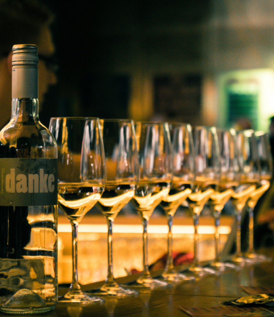 Acht gefüllte Weißweingläser an der Bar im Designhotel Wien