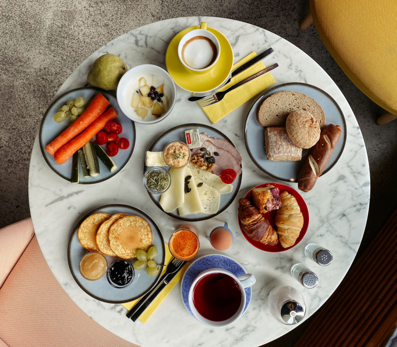 Set breakfast table with coffee, tea, pancakes, vegetables and rolls