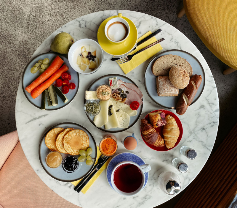 Set breakfast table with coffee, tea, pancakes, vegetables and rolls