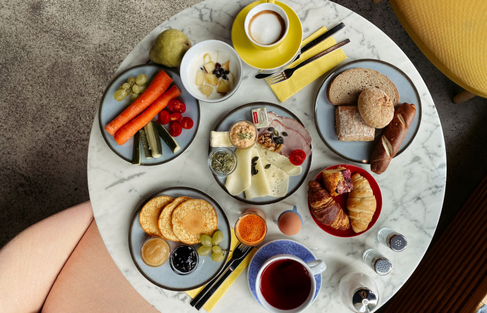 Set breakfast table with coffee, tea, pancakes, vegetables and rolls