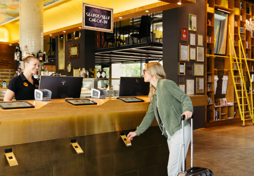 Frau beim Self Check-in in der Lobby im Hotel Schani Wien