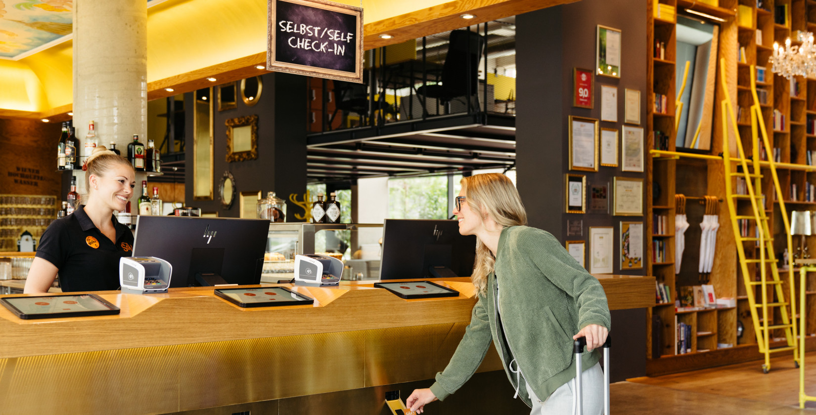 Eine Mitarbeitern an der Rezeption lächelt einen Gast an, der gerade im Hotel eincheckt