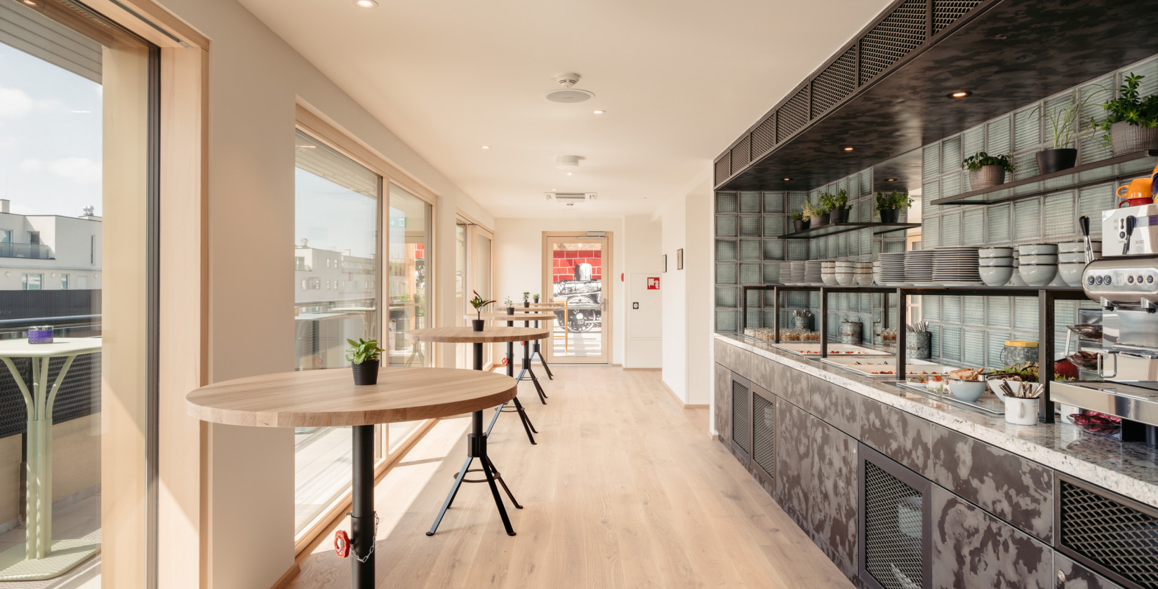 High tables opposite the buffet in the Rooftop event space at Hotel Schani Wien