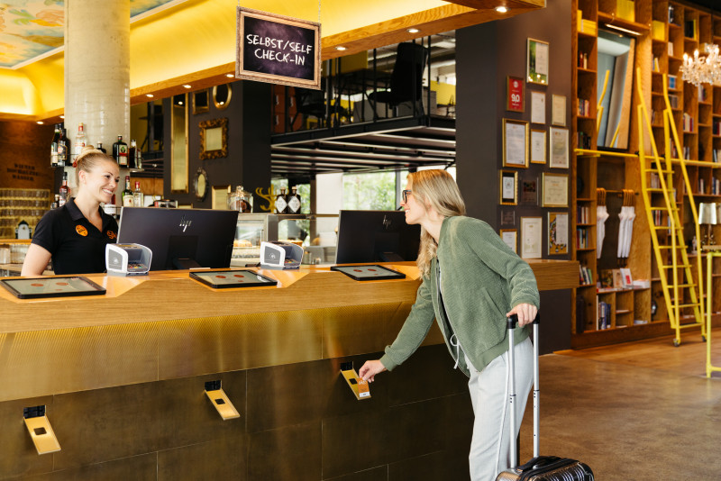 Frau beim Self Check-in in der Lobby im Hotel Schani Wien