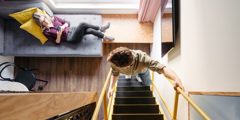 Man climbing ladder to four poster bed in smart maisonette room