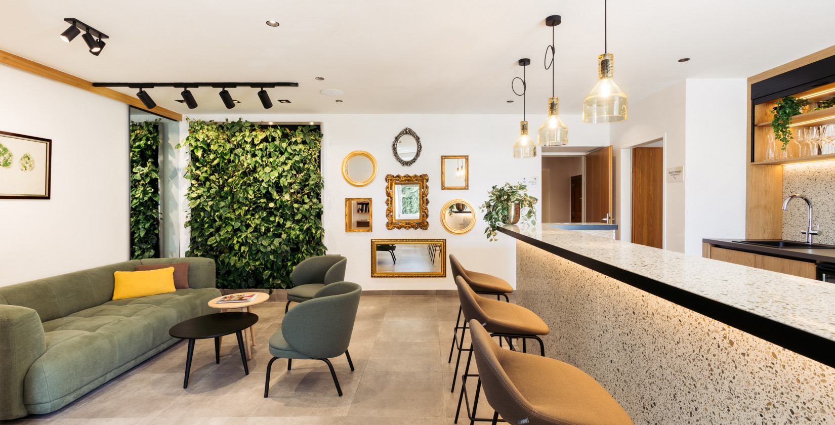 Moderne Lobby mit grüner Wand, gemütlicher Sitzecke und Bar im Hotel Schani UNO City