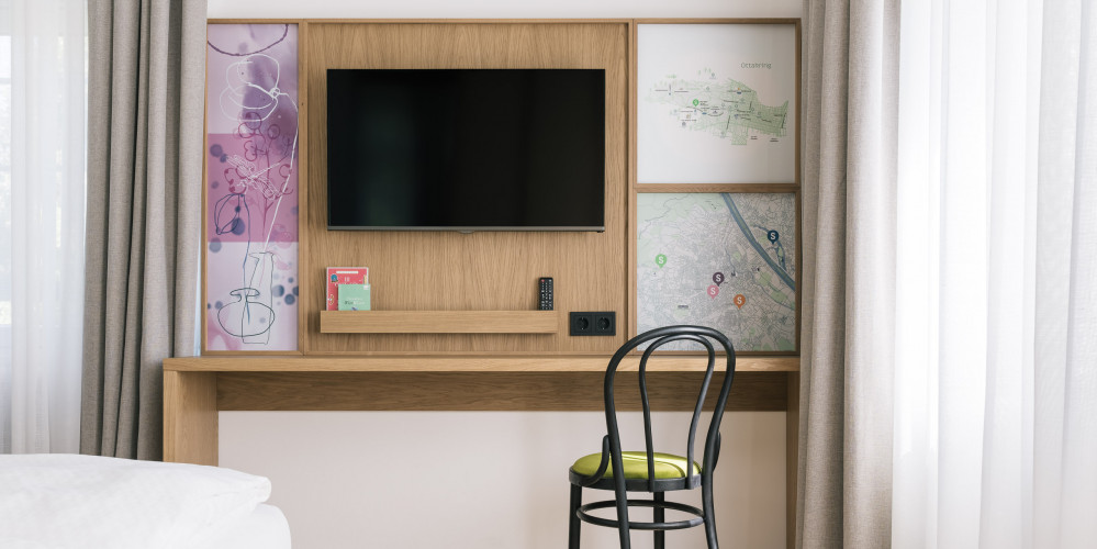 Desk with chair and a TV on the wall in the Smart Double room