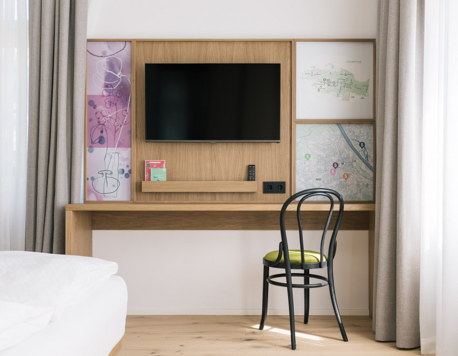 Arbeitsplatz und Fernseher neben einem Fenster im Smart Comfort Zimmer