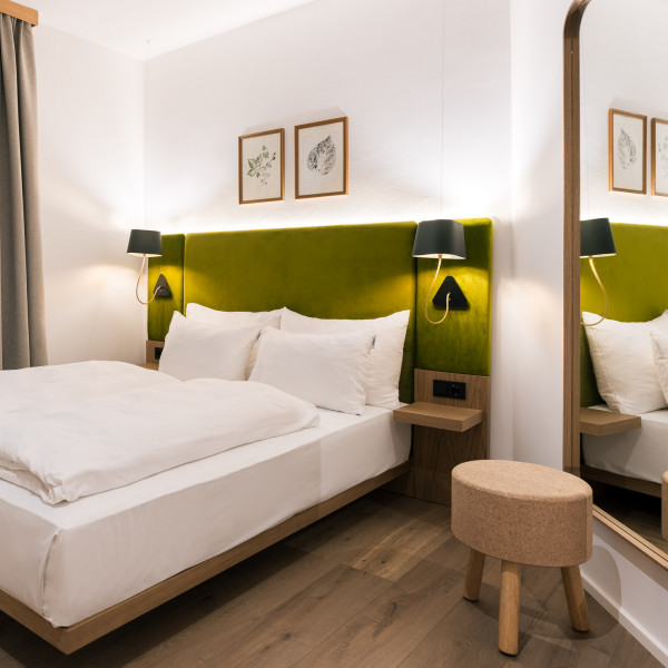 Blick in das gemütlich eingerichtete Smart Economy Zimmer mit Doppelbett und Wandspiegel
