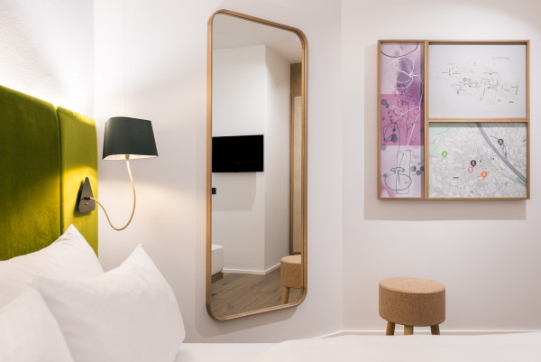 Blick über das Doppelbett im Smart Economy Zimmer auf einen Spiegel im Bio-Hotel Schani Wienblick