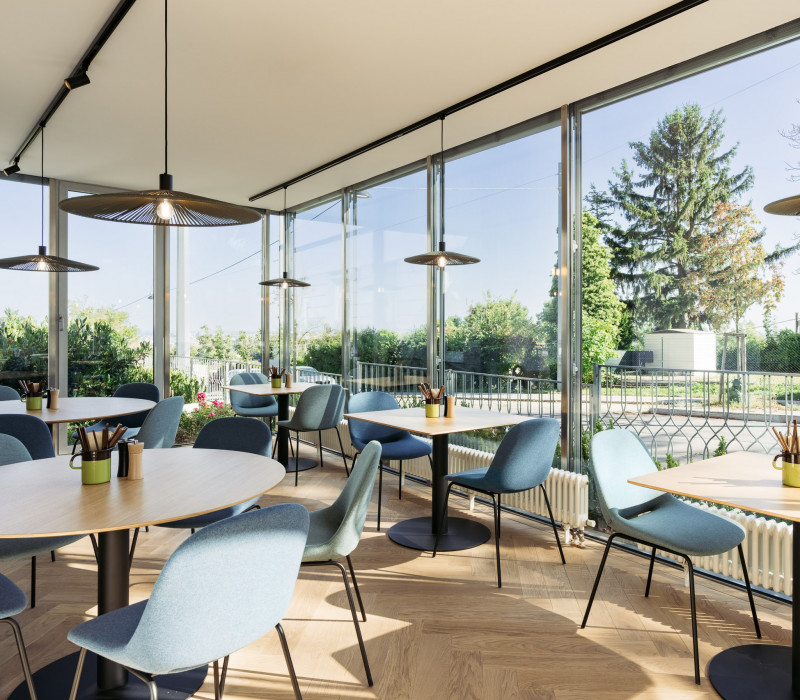 Frühstücksbereich mit Stühlen & Tischen im Wintergarten des Bio-Hotels in Wien