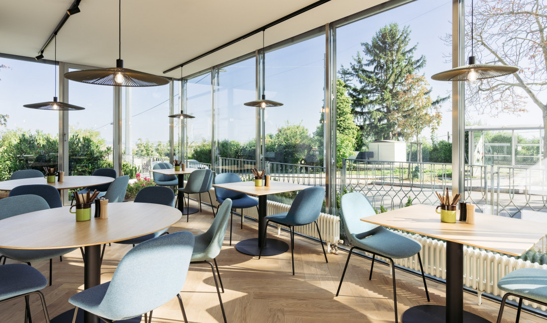 Frühstücksbereich mit Stühlen & Tischen im Wintergarten des Bio-Hotels in Wien