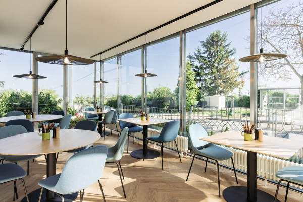 Der lichtdurchflutete Wintergarten des Bio-Hotels Wien mit Tischen und Stühlen