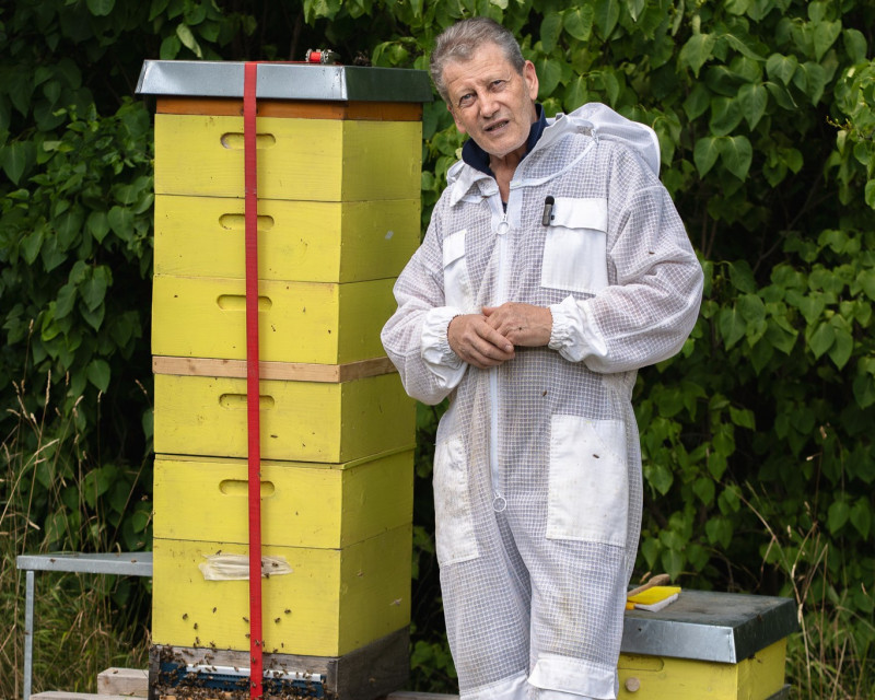 Imker Christian neben den Bienenstöcken beim Bio-Hotel Schani Wienblick