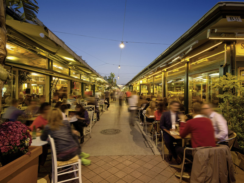 Personen sitzen vor den Lokalen am Wiener Naschmarkt