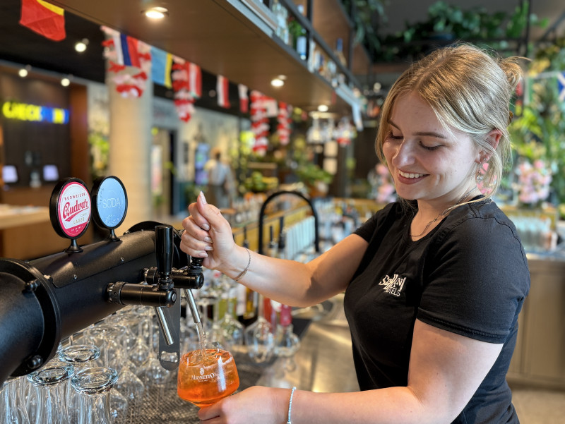 Lou hinter der Bar, richtet Getränk her 