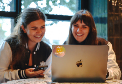 Zwei lächelnde Frauen vor einem Laptop