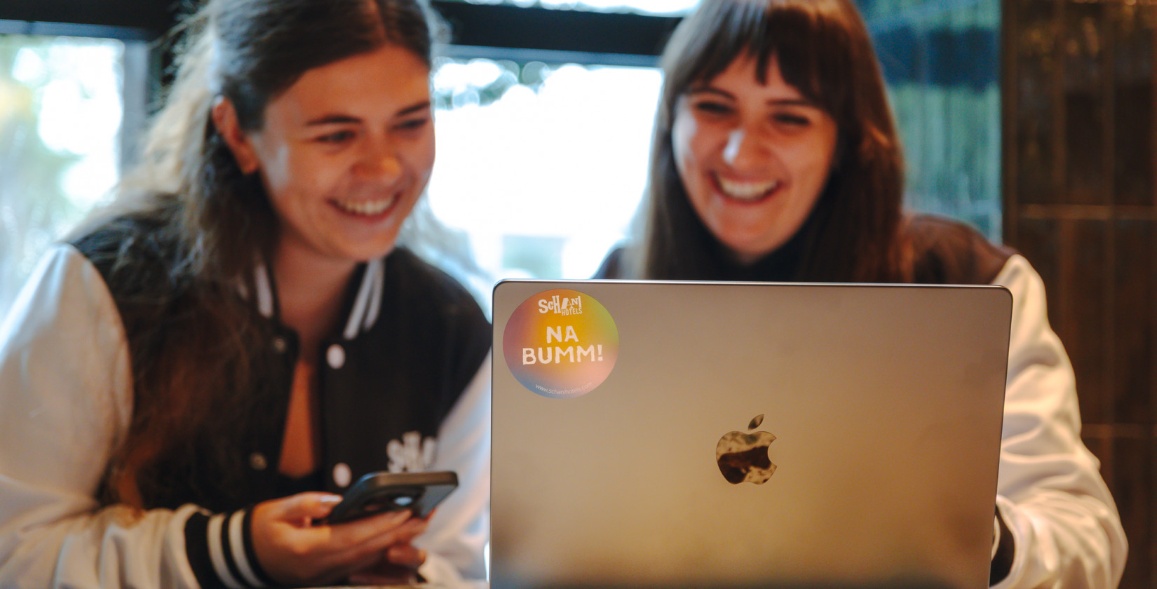 Zwei lächelnde Frauen vor einem Laptop
