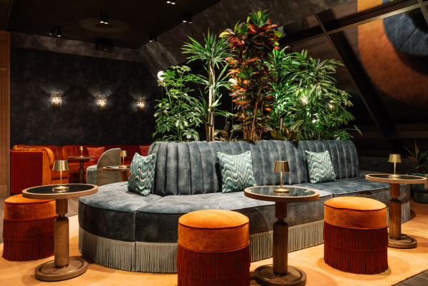 Eine blaue Sitzbank und Tische in der Rooftop Bar bei Nacht