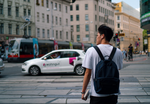 Man standing at a street in Vienna with a tram in the background