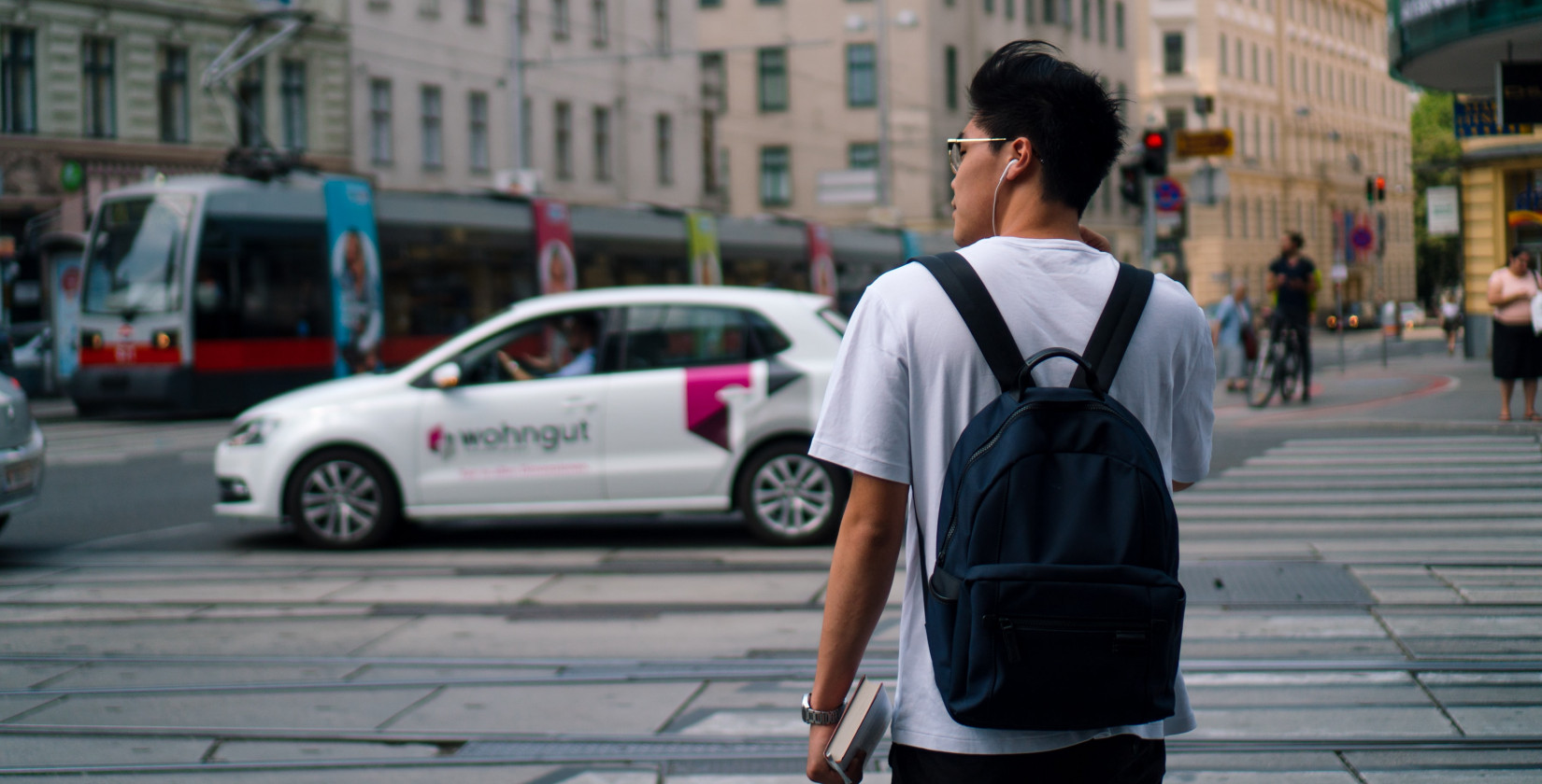 Man standing at a street in Vienna with a tram in the background